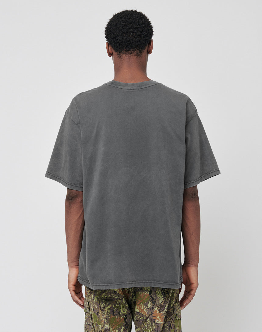 A person stands with their back to the camera wearing the LIVE FAST DIE YOUNG Burning Dice Tee in Regular Fit, faded black, paired with camouflage pants, set against a plain light gray background.