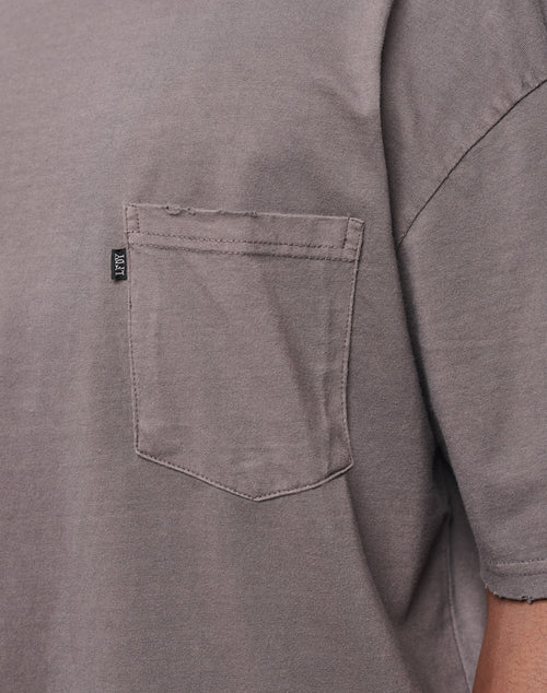 Close-up of the LFDY Destroyed Pocket Tee in gray, showcasing its oversize fit, small chest pocket with visible stitching, and a black fabric tag on the left seam of the pocket.