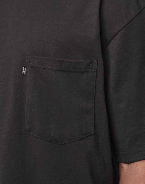 Close-up of the LFDY Destroyed Pocket Tee in black, showcasing its oversized fit with a left chest pocket featuring a small fabric tag on the seam. The design also reveals part of the sleeve and shoulder seam.