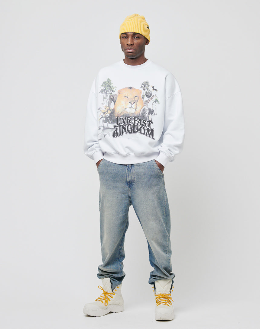 A man in a yellow knit beanie, light blue jeans, white boots, and the LFDY Vintage Lion Sweater stands against a plain background for a cool vintage look.
