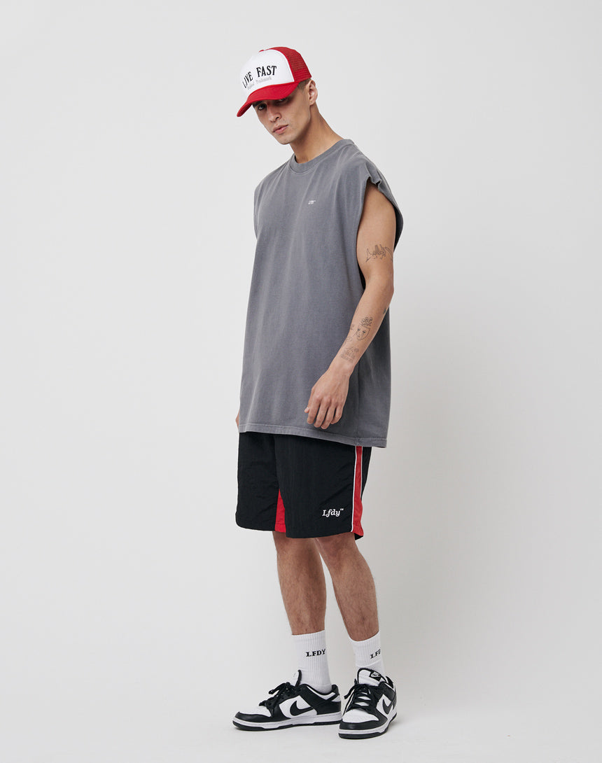 A man stands against a white background wearing a red and white cap, loose gray sleeveless shirt, LFDY Beach Shorts with mesh inlay and elastic waistband, white socks, and black-and-white sneakers.
