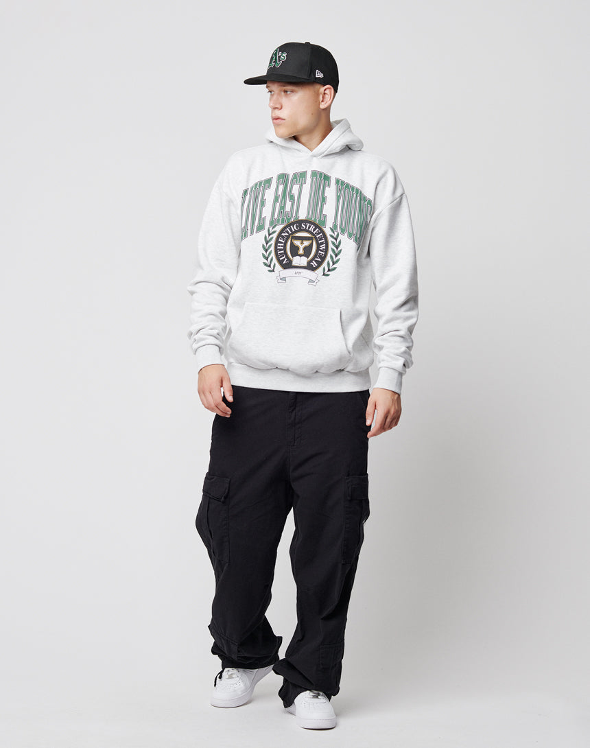 A young man in a black cap, light gray hoodie with a large printed crest, LFDY Wide Summer Cargo pants, and white sneakers stands against a plain white background, looking to his left.