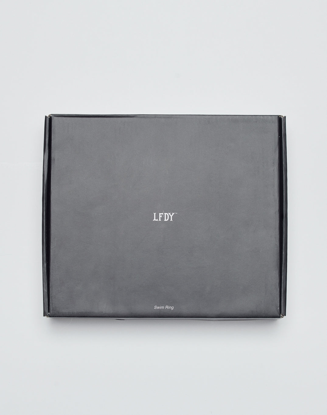 A closed, rectangular black box featuring LIVE FAST DIE YOUNG and Live Fast Swim Ring text on the front, placed against a plain white background.