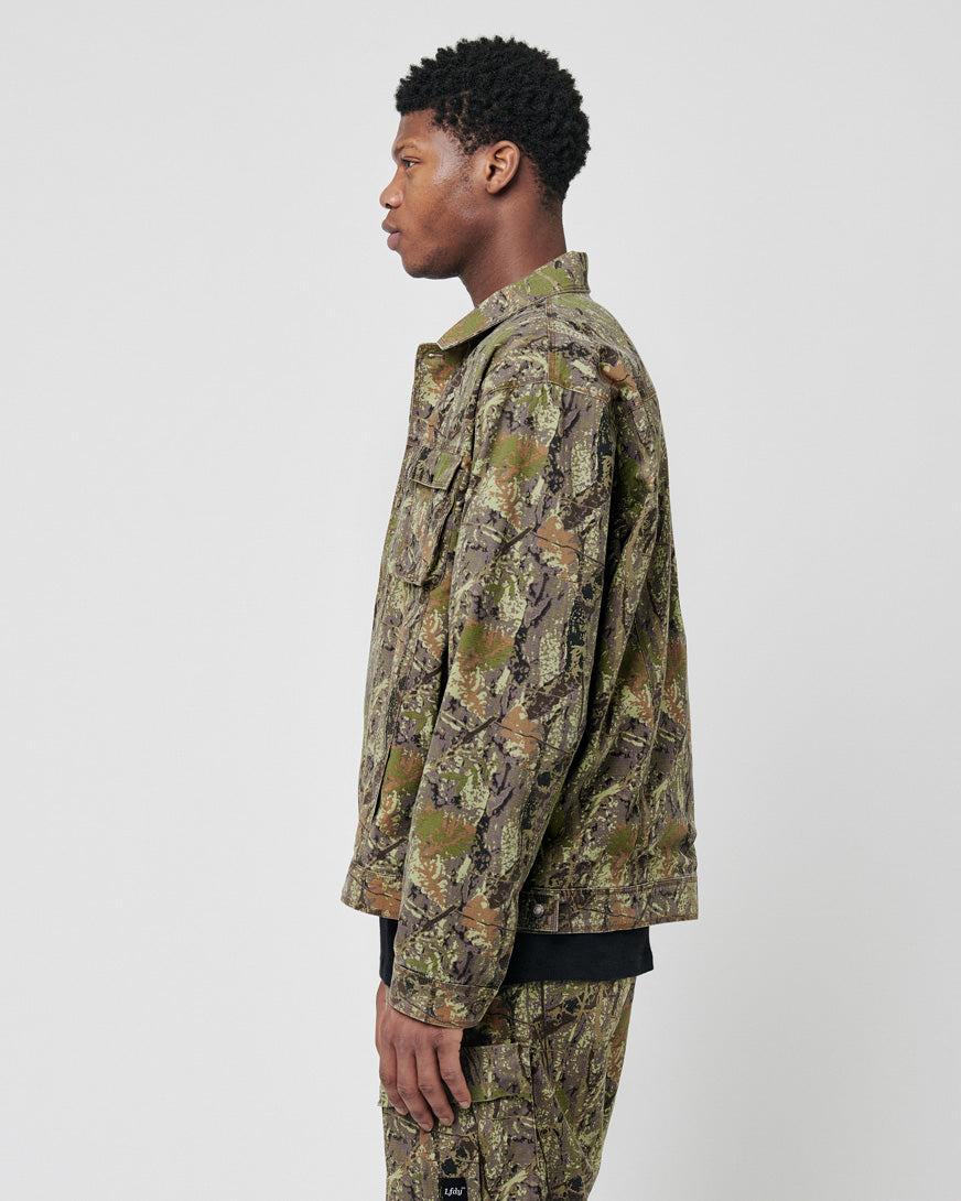 A man in profile wears the LIVE FAST DIE YOUNG LFDY Hunter Jacket and matching pants, both in camo and made from 100% Baumwolle, set against a plain white background.
