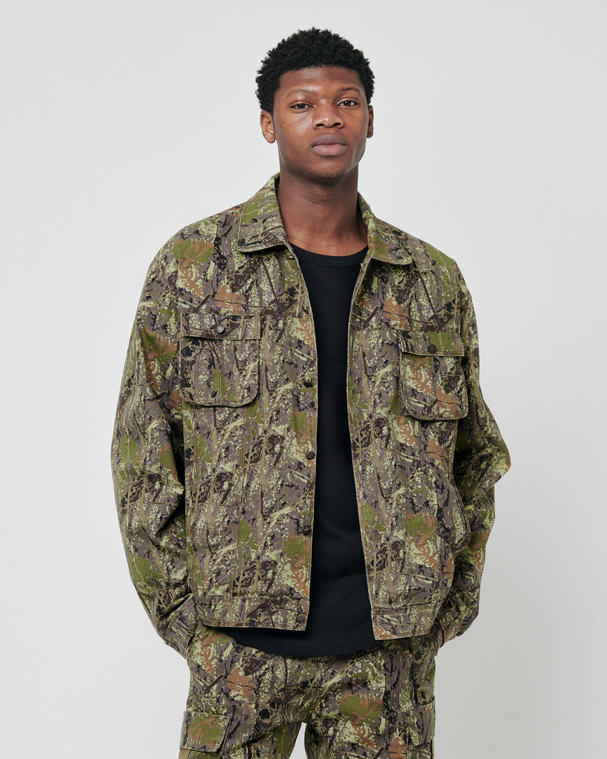 A man stands facing the camera with his hands in his pockets, wearing a LIVE FAST DIE YOUNG LFDY Hunter Jacket and matching pants made from 100% cotton, set against a plain light gray background.