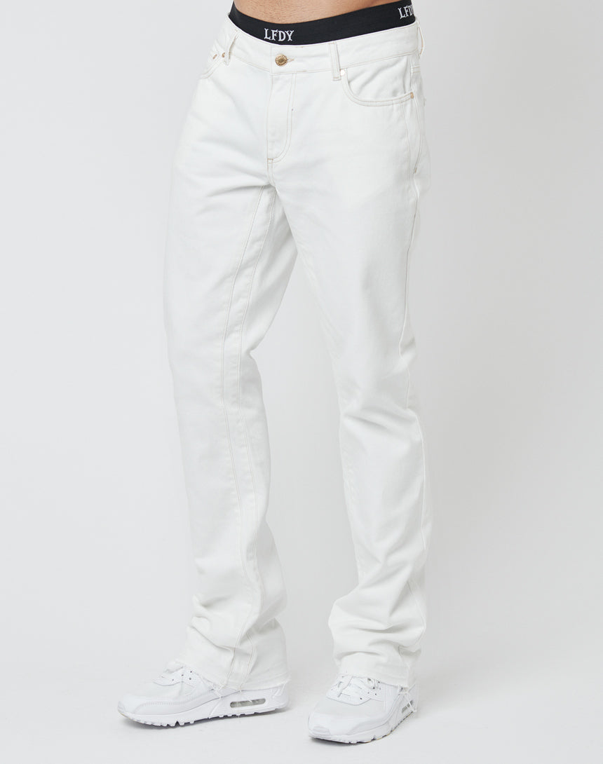 A person stands against a plain white background wearing LFDY Striped Flared Denim jeans, white sneakers, and a black LFDY waistband. The upper body is not visible.