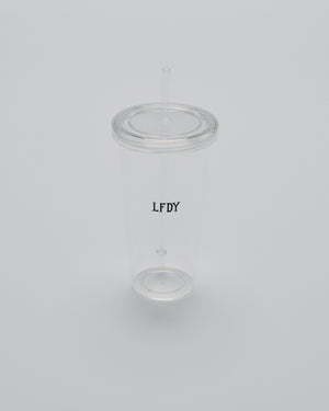 The LFDY Cold Cup by LIVE FAST DIE YOUNG is a clear plastic tumbler with a transparent lid and straw, featuring vertical black LFDY text on the side. Photographed on a plain light gray background. Berlin Store Exclusive.