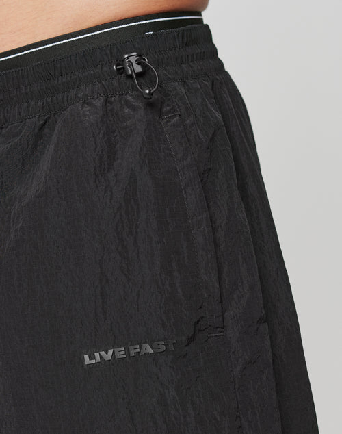 Close-up of the Live Fast Nylon Shorts by LIVE FAST DIE YOUNG, in black with an oversized fit, drawstring waist, and bold LIVE FAST silicone print by the pocket. Made from durable polyamide for lasting comfort.