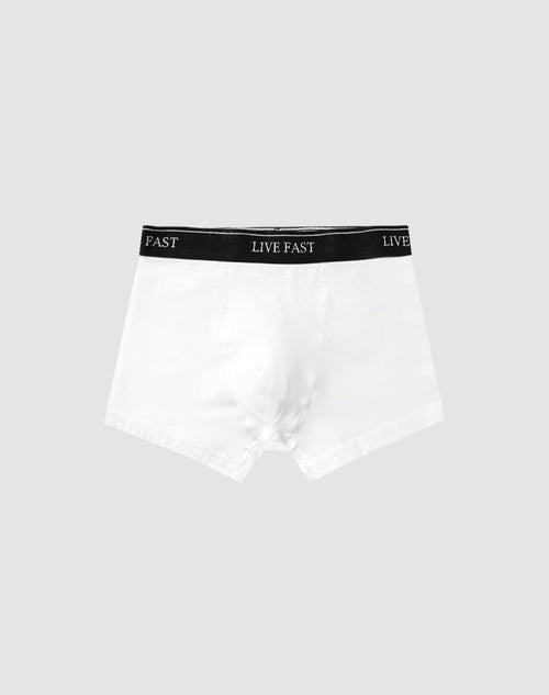 A pair of Live Fast Trunks (2 Pack) by LIVE FAST DIE YOUNG in white cotton features a black elastic waistband with LIVE FAST in white, set against a plain light gray background.