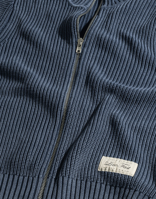 A close-up of the LFDY Knit Jacket by LIVE FAST DIE YOUNG shows a blue ribbed zip-up sweater with a Stehkragen, metal zipper, and a sewn-on white label reading "Inter Tradi Classic.