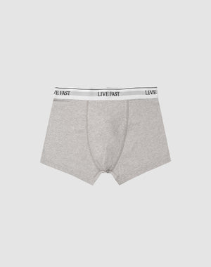 LIVE FAST DIE YOUNGs Live Fast Trunks (2 Pack) feature gray mens boxer briefs in soft cotton with a LIVE FAST black elastic waistband. Care instructions for easy maintenance included; shown on a light gray background.