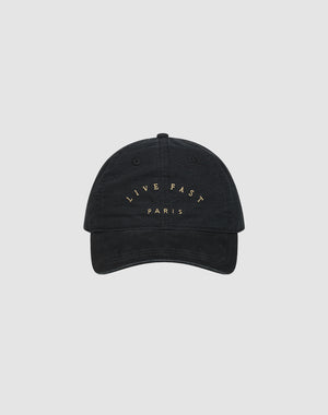 The Live Fast Paris Cap by LIVE FAST DIE YOUNG is a black 100% Baumwolle baseball cap with "LIVE FAST PARIS" embroidered in gold on the front, shown against a plain light gray background.