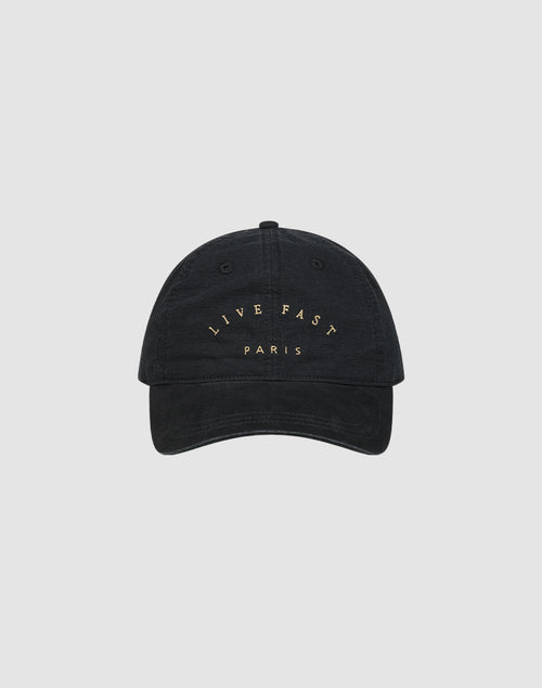 The Live Fast Paris Cap by LIVE FAST DIE YOUNG is a black 100% Baumwolle baseball cap with "LIVE FAST PARIS" embroidered in gold on the front, shown against a plain light gray background.