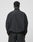 A person with short, curly hair is seen from behind wearing the LIVE FAST DIE YOUNG Live Fast Nylon Halfzip and black pants. The oversized jacket, made of polyester and polyamide, stands out against a plain white background.