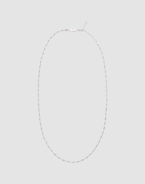 The LIVE FAST DIE YOUNG Basic Figaro Chain is a delicate 925 Sterling Silber necklace with a simple clasp, shown in an oval on a light gray background. Die Kettenlänge ist verstellbar für deine perfekte Passform.