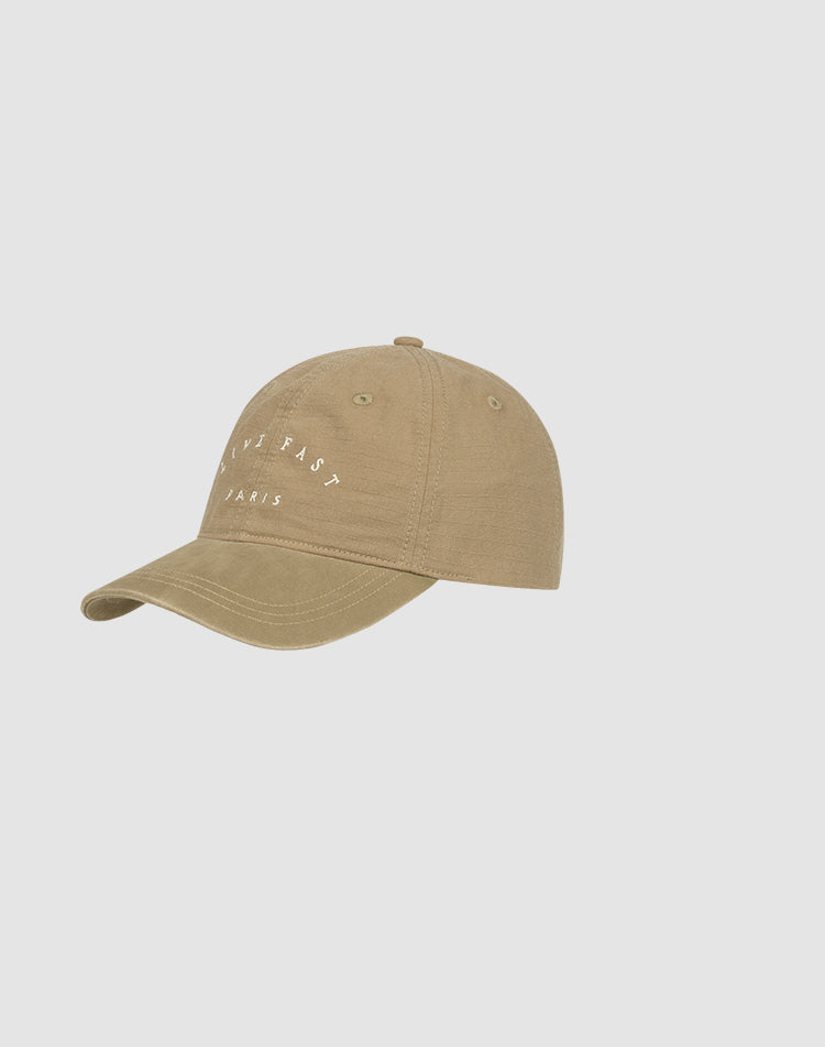 The Live Fast Paris Cap by LIVE FAST DIE YOUNG is a light brown 100% cotton baseball cap with a curved brim and white "DRIVE FAST PARIS" text on the front, shown against a plain light gray background.