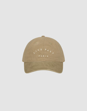 The Live Fast Paris Cap by LIVE FAST DIE YOUNG is a beige 100% Baumwolle baseball cap featuring "LIVE FAST" in white above "PARIS" on the front, shown against a plain light gray background.