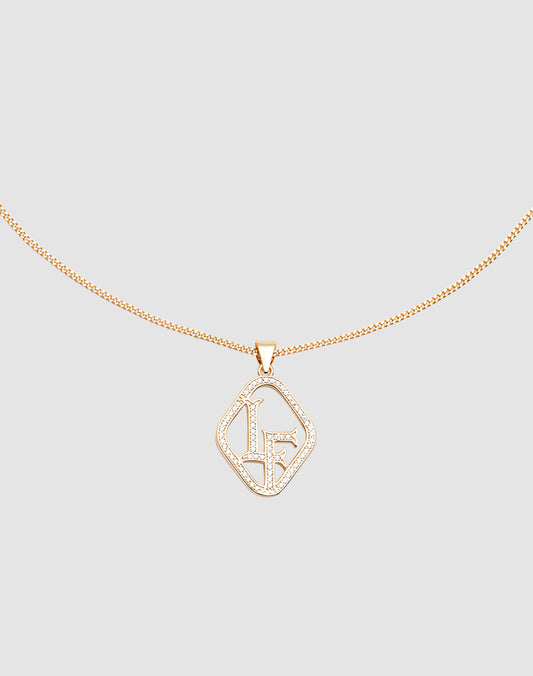 The LF Chain by LIVE FAST DIE YOUNG is a delicate gold necklace with a Zirkonia Anhänger displaying the initials LF in sparkling crystals, set against a light gray background.