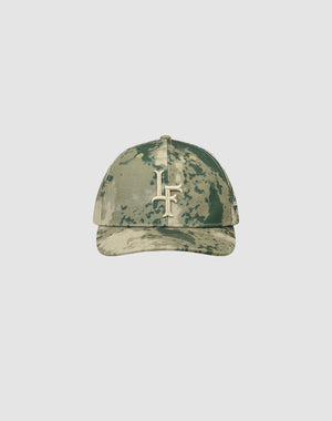 The LF Snapback by LIVE FAST DIE YOUNG is a camouflage baseball cap with a curved brim, featuring a bold white Logo-Stick LF logo on the front. Crafted from 100% Baumwolle, it’s shown against a plain light gray background.