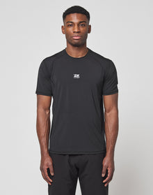A man faces forward against a white background, wearing the LIVE FAST DIE YOUNG Live Fast Performance Tee in black, featuring a slim fit, short sleeves, small white chest logo, and comfortable Nylon Spandex material with matching black pants.