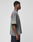 A young man stands sideways in a LIVE FAST DIE YOUNG LFDY Metro Boomin Tee, an oversize fit faded gray graphic shirt with colorful text and sleeve print, made of 100% Baumwolle, paired with dark jeans. The background is plain light gray.