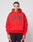 A person faces the camera in an oversized bright red Live Fast College Hooded by LIVE FAST DIE YOUNG, featuring bold black LIVE FAST text and black/red athletic shorts, made from a comfortable polyester blend, against a plain white background.