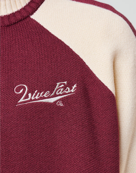 Close-up of the Boxy Knit Zip Jacket by LIVE FAST DIE YOUNG, featuring maroon and cream sections. Maroon fabric displays white embroidered "Live Fast Co." text near the chest in a stylish logo-knit detail.