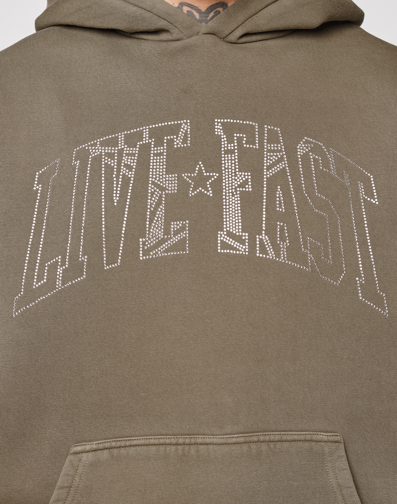 Close-up of the Live Fast Rhinestone Hooded by LIVE FAST DIE YOUNG—an olive green hoodie with a sparkling rhinestone "LIVE FAST" and star logo, featured in large outlined letters atop its vintage washed finish.