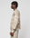 A person with short, twisted hair wears the LIVE FAST DIE YOUNG Live Fast Boucle Sweater—an oversize, cloud-patterned beige and gray top with matching pants—made from soft polyester, posing in profile against a plain white background.