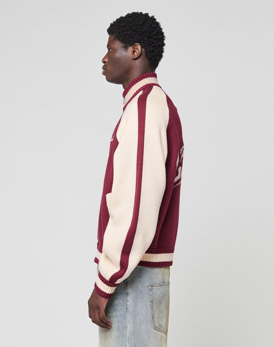 A person stands in profile wearing the LIVE FAST DIE YOUNG Boxy Knit Zip Jacket with an oversize fit and light blue jeans against a plain light gray background.