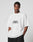 Wearing the LIVE FAST DIE YOUNG Fuck Die Young Tee, an oversized white 100% Baumwolle T-shirt with bold front print, a person stands against a plain light background, looking at the camera with hands in pockets.