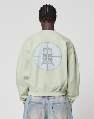 Someone seen from behind wears the LIVE FAST DIE YOUNG LFDY Vandals Sweater in Oversize Fit, featuring a large train-in-crosshair graphic on the back, paired with light blue, slightly distressed jeans with a unique wash effect.