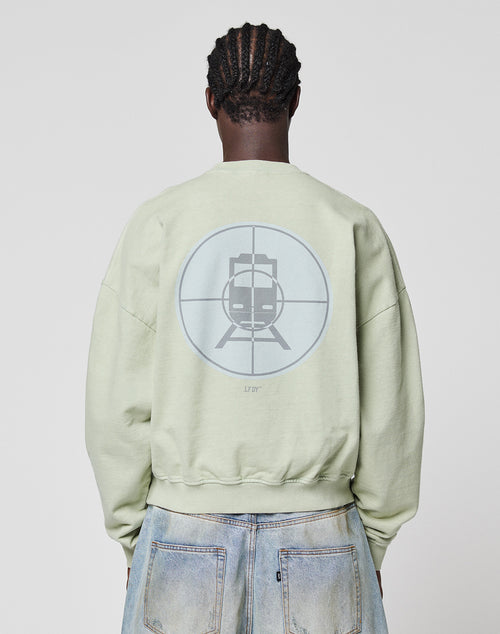 Someone seen from behind wears the LIVE FAST DIE YOUNG LFDY Vandals Sweater in Oversize Fit, featuring a large train-in-crosshair graphic on the back, paired with light blue, slightly distressed jeans with a unique wash effect.