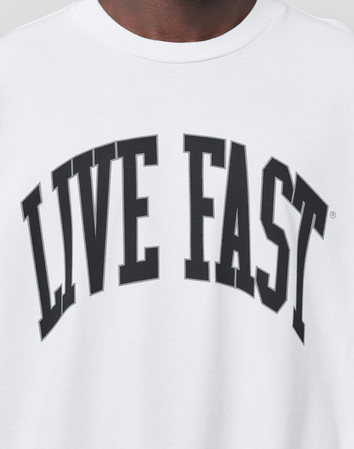 A close-up of the Live Fast College Tee by LIVE FAST DIE YOUNG, an oversize fit white shirt featuring bold, black, arched LIVE FAST lettering across the chest.