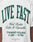 Close-up of the LIVE FAST DIE YOUNG Live Fast Coffee Tee, a white 100% Baumwolle T-shirt with green LIVE FAST text, West Berlin Coffee & Cigarettes script, oversize fit, and small LFDY Berlin Café branding at the bottom.