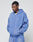 A man stands with his hands in the pockets of a blue LIVE FAST DIE YOUNG Basic Hooded Zip and matching sweatpants, featuring a subtle faded look, looking down with a neutral expression against a plain light background.