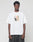 A man stands against a plain background wearing the LFDY Sharkhunter Tee by LIVE FAST DIE YOUNG, an oversize white 100% Baumwolle T-shirt featuring a blurry rectangle graphic and LFYT text on the front, paired with dark baggy jeans.