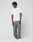 A person with short, textured hair stands against a plain background, wearing the LIVE FAST DIE YOUNG Live Fast Plain Tee, loose gray pants, and white sneakers. They have a relaxed posture and a neutral expression.