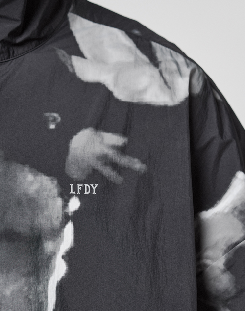 A close-up of the black LFDY Performance Jacket by LIVE FAST DIE YOUNG, featuring white "LFDY" lettering and an allover grayscale abstract print that may depict a hand.