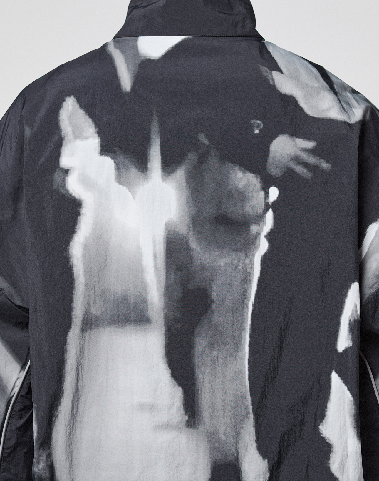 The LFDY Performance Jacket by LIVE FAST DIE YOUNG features a black-and-white abstract nylon pattern with blurred shapes, a reflective logo print on the back, and delivers a modern edge.