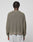 A person with short, twisted hair is seen from the back wearing the LIVE FAST DIE YOUNG LFDY Knit Sweater in an oversize olive-green ribbed design with dropped shoulders, paired with light gray pants against a plain background.