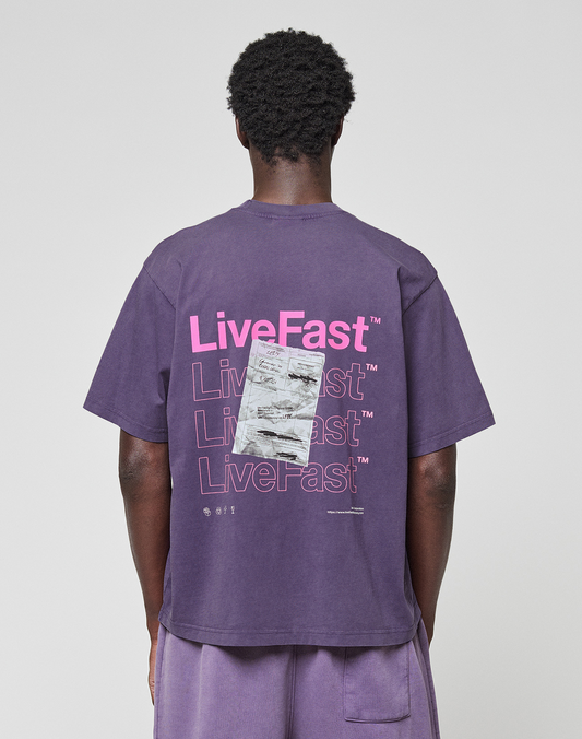 A person in a purple Basic Evidence Tee by LIVE FAST DIE YOUNG, made from 100% Baumwolle, featuring repeated “LiveFast” text and a graphic on the back. The front and back print design is shown from behind against a plain background.