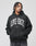 A person with braided hair wears the LIVE FAST DIE YOUNG Live Fast Axe Hooded, an oversize black hoodie with bold white LIVE FAST lettering, standing against a plain light gray background and looking to the side with hands in pockets.