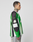 A tattooed man stands in profile wearing the LIVE FAST DIE YOUNG LFDY Motorcross Jersey—an oversized green, black, and white long-sleeve with multi-logo prints and "40" on the sleeve—paired with light blue jeans against a plain background.
