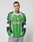 A man with short hair and neck tattoos wears the LFDY Motorcross Jersey by LIVE FAST DIE YOUNG—an oversized green, black, and white long-sleeve with multi-logo prints, "LIVE FAST 3000," and the number 40—standing against a plain light background.
