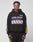 A person in an oversize fit black LFDY Racing Hooded by LIVE FAST DIE YOUNG, featuring glossy white and lavender LIVE FAST Everything print with yellow and lavender stripes, plus matching black pants, stands against a light gray background.