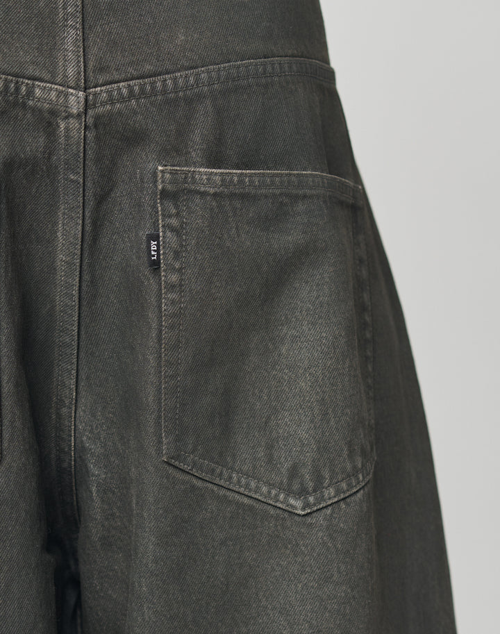 Close-up of the back pocket on LFDY Coated Baggy Denim by LIVE FAST DIE YOUNG, featuring dark gray 100% Baumwolle fabric, detailed stitching, a small black tag with white text, and a gerades Bein for a modern look.