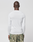 A person with a shaved head stands with their back to the camera, wearing a LIVE FAST DIE YOUNG LFDY Performance Slim Longsleeve in white, featuring mesh insert details, and green camouflage shorts against a plain light background.