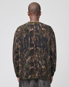 A person with a shaved head is seen from behind in an oversize LFDY Fleece Longsleeve by LIVE FAST DIE YOUNG, featuring a camouflage print and bold LIVE FAST lettering on the back. The setting is plain with a light background. | model