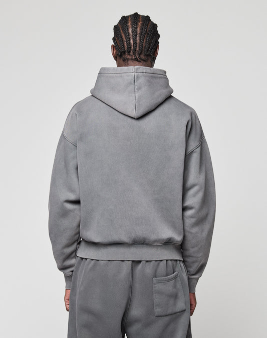 A person with braided hair is seen from behind wearing the LIVE FAST DIE YOUNG Basic +49 Hooded oversize grey hoodie and sweatpants set with a back pocket, made of Baumwolle, against a plain light background. The hood is down.
